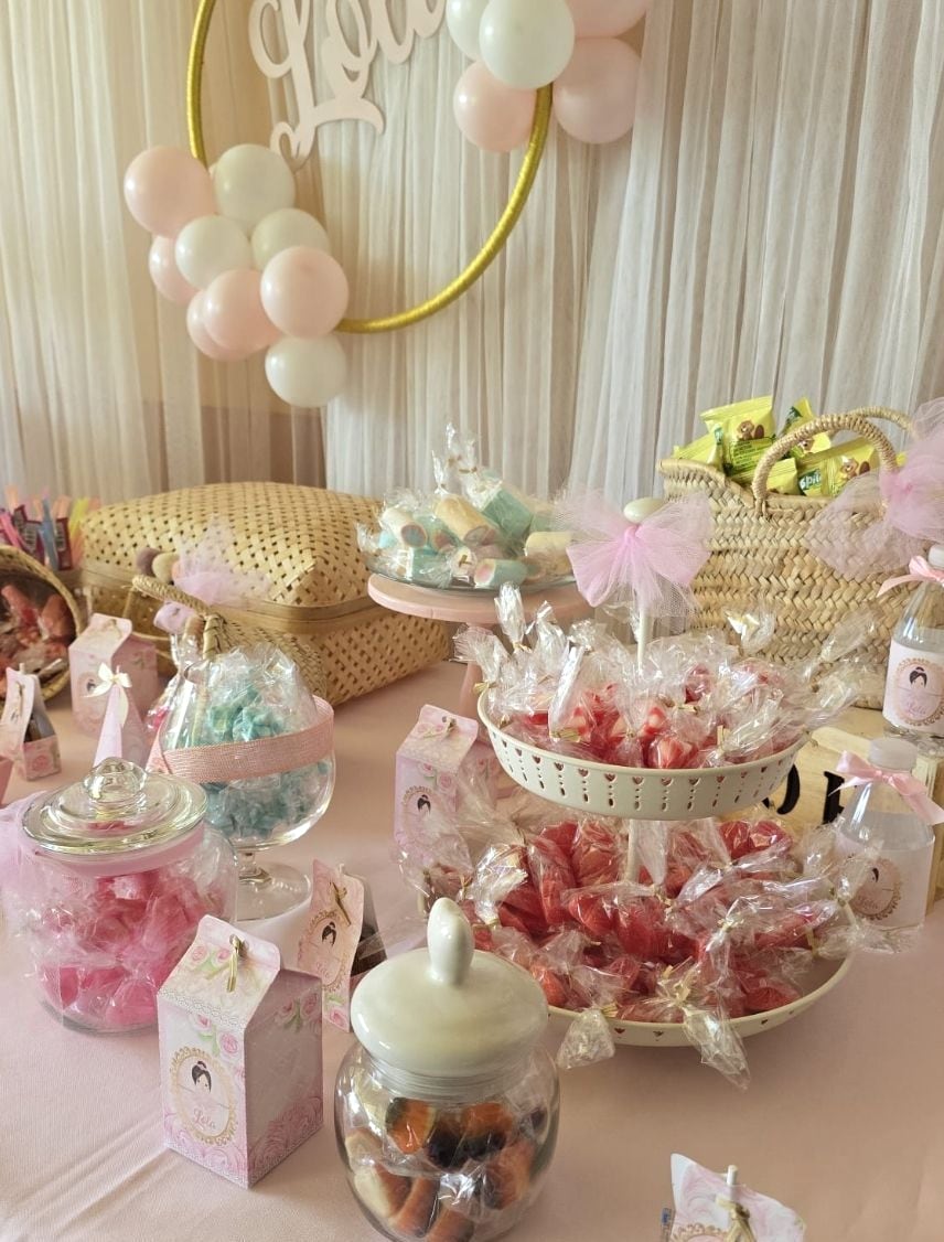 Candy bar en tonos rosa pastel con tarros de golosinas y cajitas personalizadas