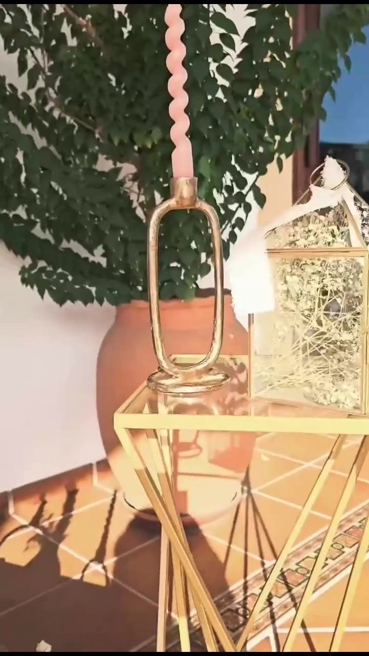 Farol dorado colgado entre plantas en una boda al aire libre